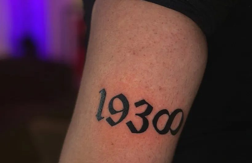님의 남성 팔뚝 문신에 새겨진 작은 블랙레터 1930