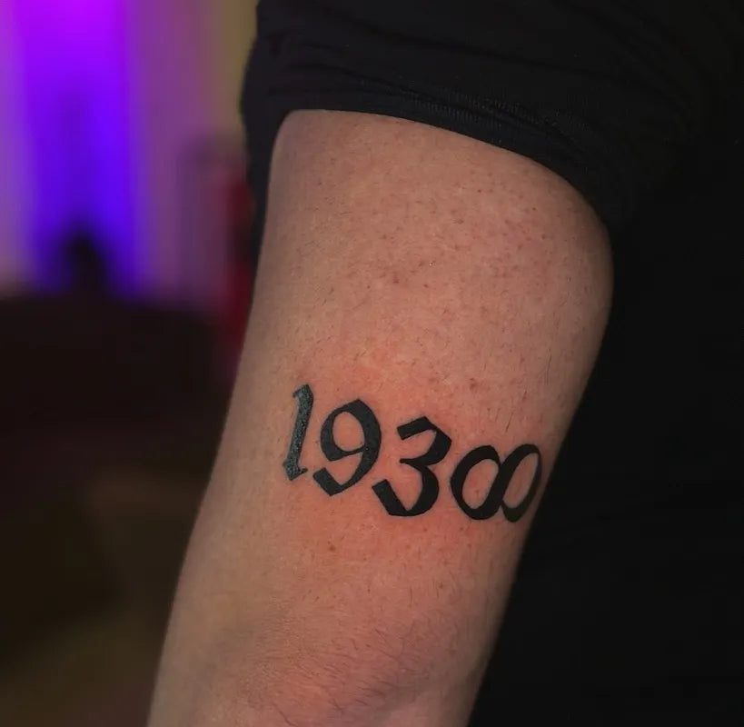 님의 남성 팔뚝 문신에 새겨진 작은 블랙레터 1930