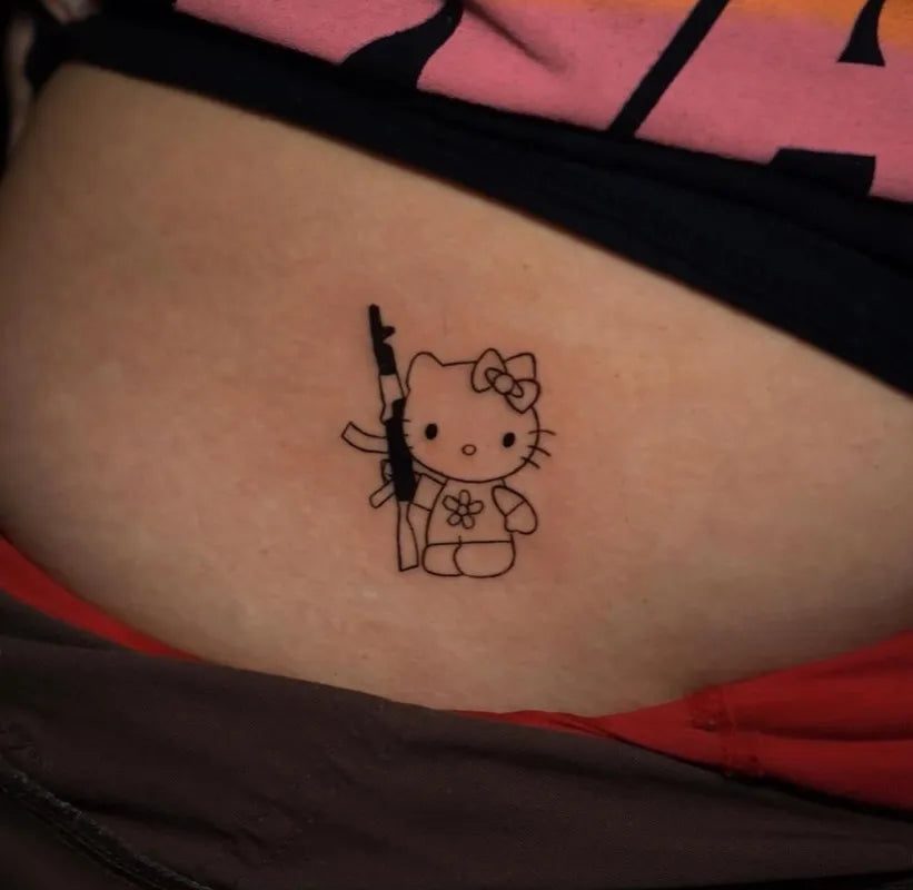 여성 복부에 총을 든 헬로 키티를 작은 선으로 그린 ​​타투