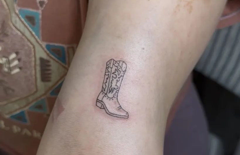 여성 팔에 새겨진 작은 라인워크 카우보이 부츠 문신