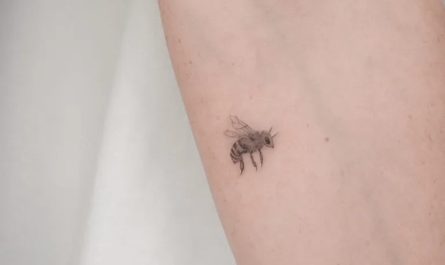여성 팔에 있는 작고 미니멀한 벌 문신