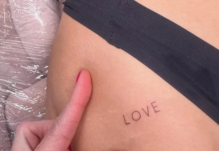 여성 엉덩이에 새겨진 작고 미니멀한 LOVE 단어 타투