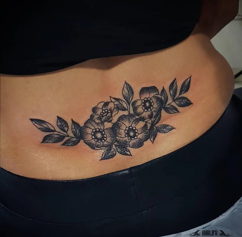 여성 허리 아랫부분에 있는 중간 크기의 검정색과 회색 히비스커스 꽃 문신