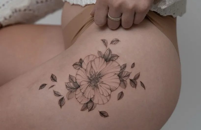 여성 엉덩이에 있는 중간 크기의 검정색과 회색 꽃 문신