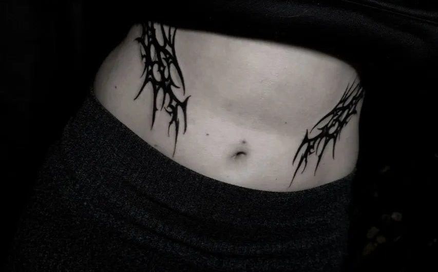 여성 복부에 새겨진 중간 크기의 블랙워크 가지 덩굴 문신
