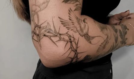 여성 팔꿈치에 있는 중간 크기의 검정색과 회색 꽃과 새 문신