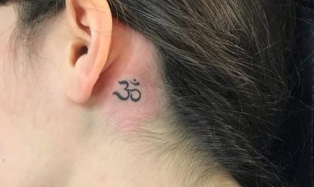 여성 귀 뒤에 새긴 작고 섬세한 블랙 앤 그레이 옴(Om) 심볼 타투