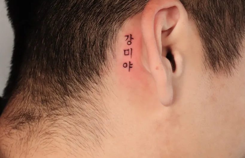 남성 귀 뒤에 새긴 작은 블랙워크 스타일의 한글 타투